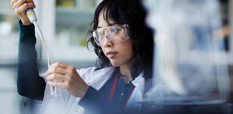 Eine Forscherin füllt ein Reagenzglas in einem Labor